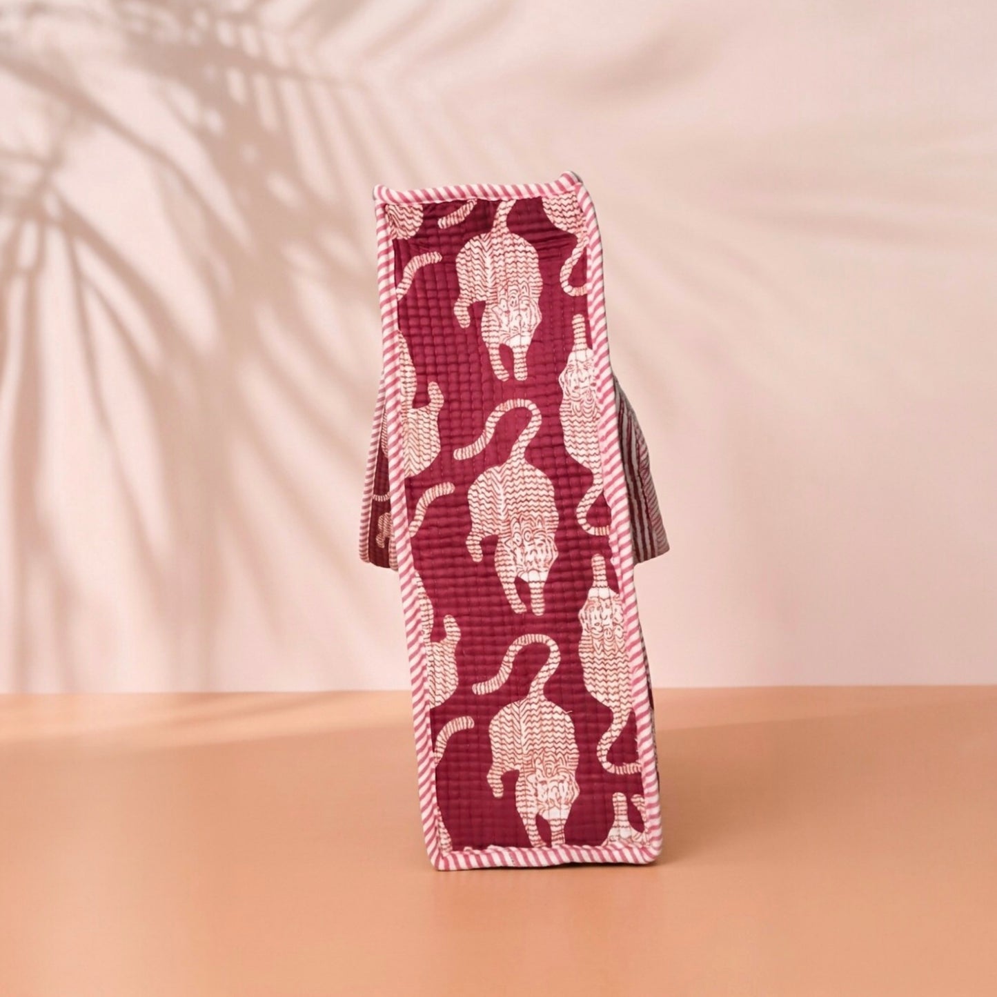 Red woven bottle holder with white cat pattern on a beige background