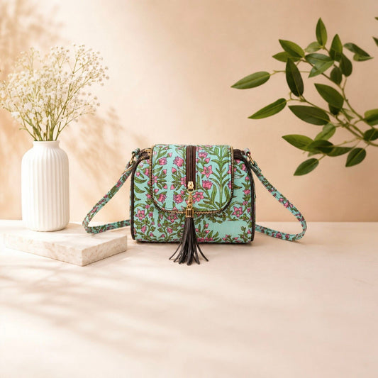 Floral patterned handbag with tassel on a beige surface with a vase and plant in the background