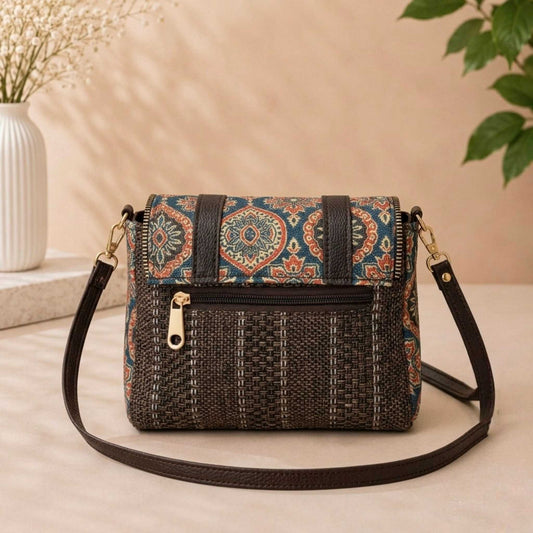 Woven handbag with patterned top section on a beige surface with a plant in the background