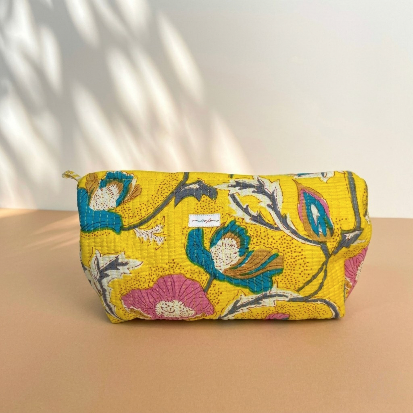 Floral-patterned pouch on a beige surface with a light background
