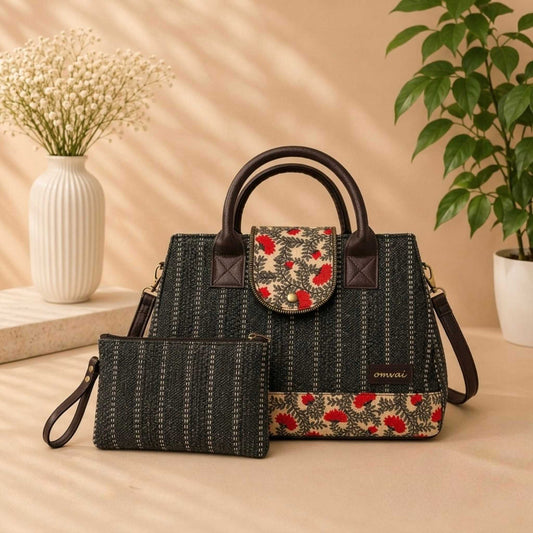 Black handbag with floral accents on a beige surface with decorative elements.