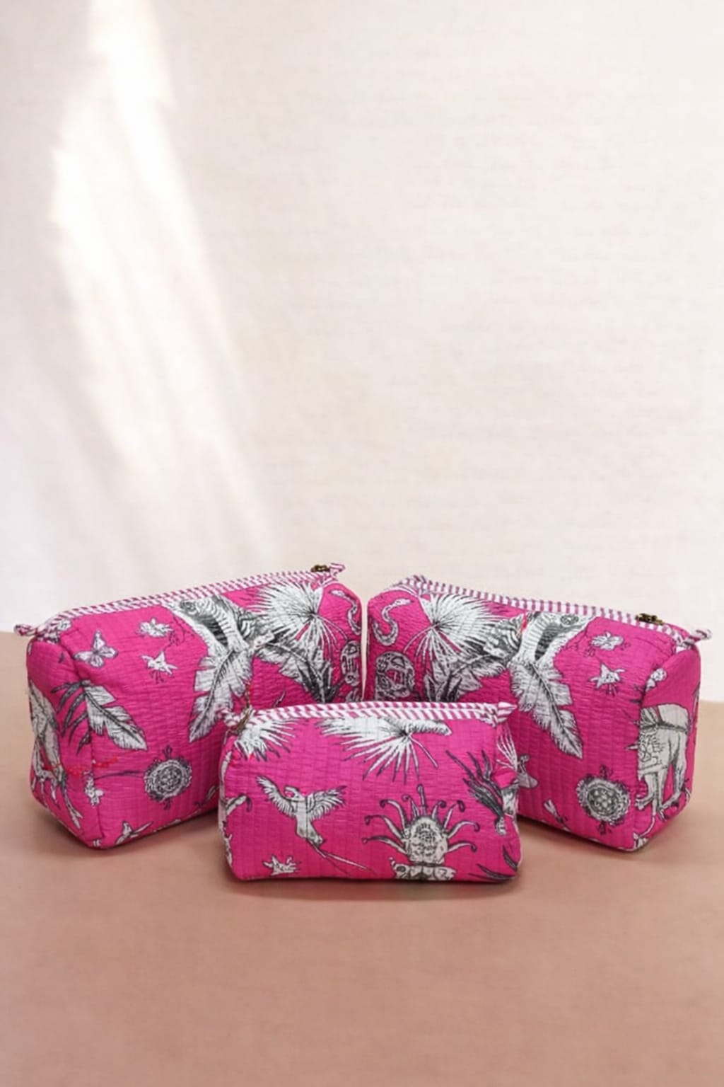 Two pink floral-patterned makeup bags on a beige background