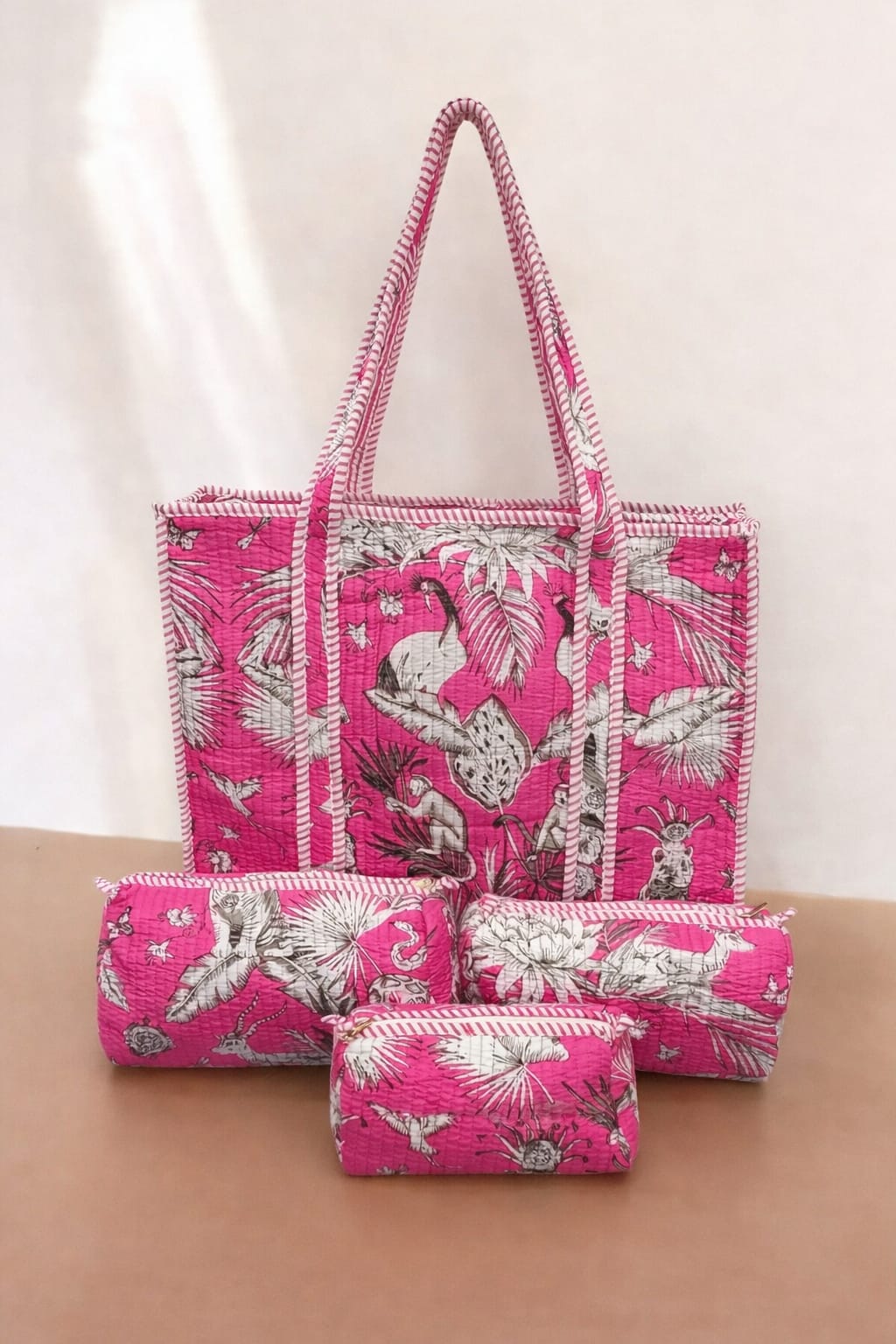 Set of pink bags with white floral patterns on a beige surface
