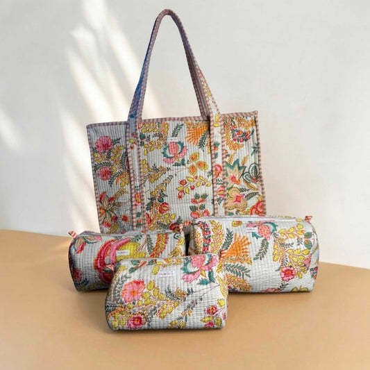 Set of floral-patterned bags including a tote, two cylindrical pouches, and a small pouch on a beige surface.