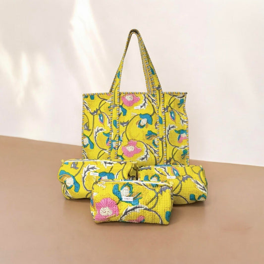Yellow floral-patterned tote bag and pouch on a beige surface with a light pink background