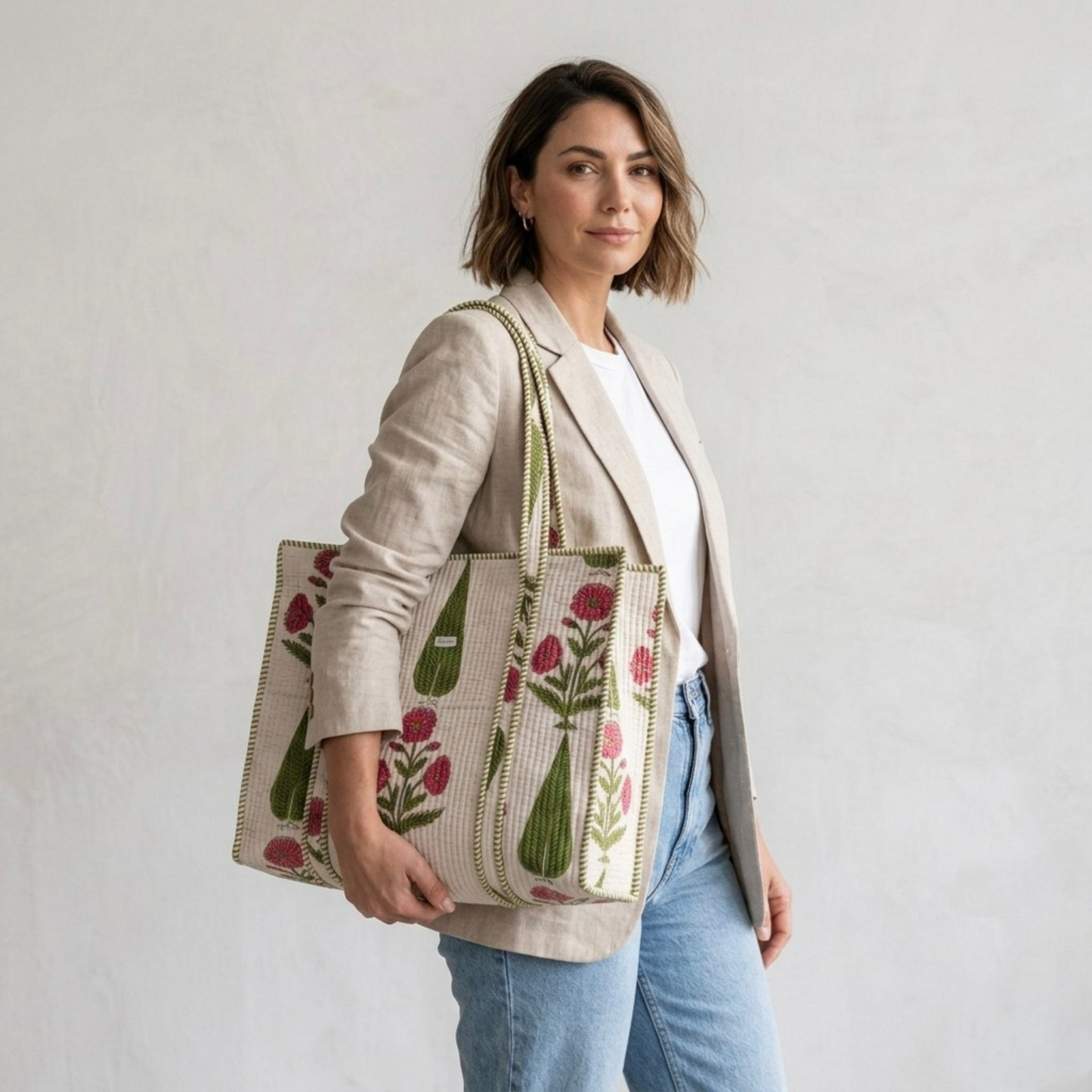 Woman holding a floral embroidered tote bag against a plain background