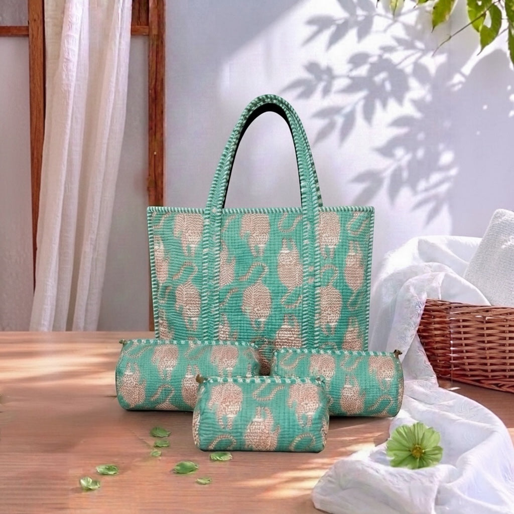 A matching woven tote bag, cylindrical pouch, and small zip pouch set in mint green and beige, styled on a wooden table with draped white fabric and leaf shadows.