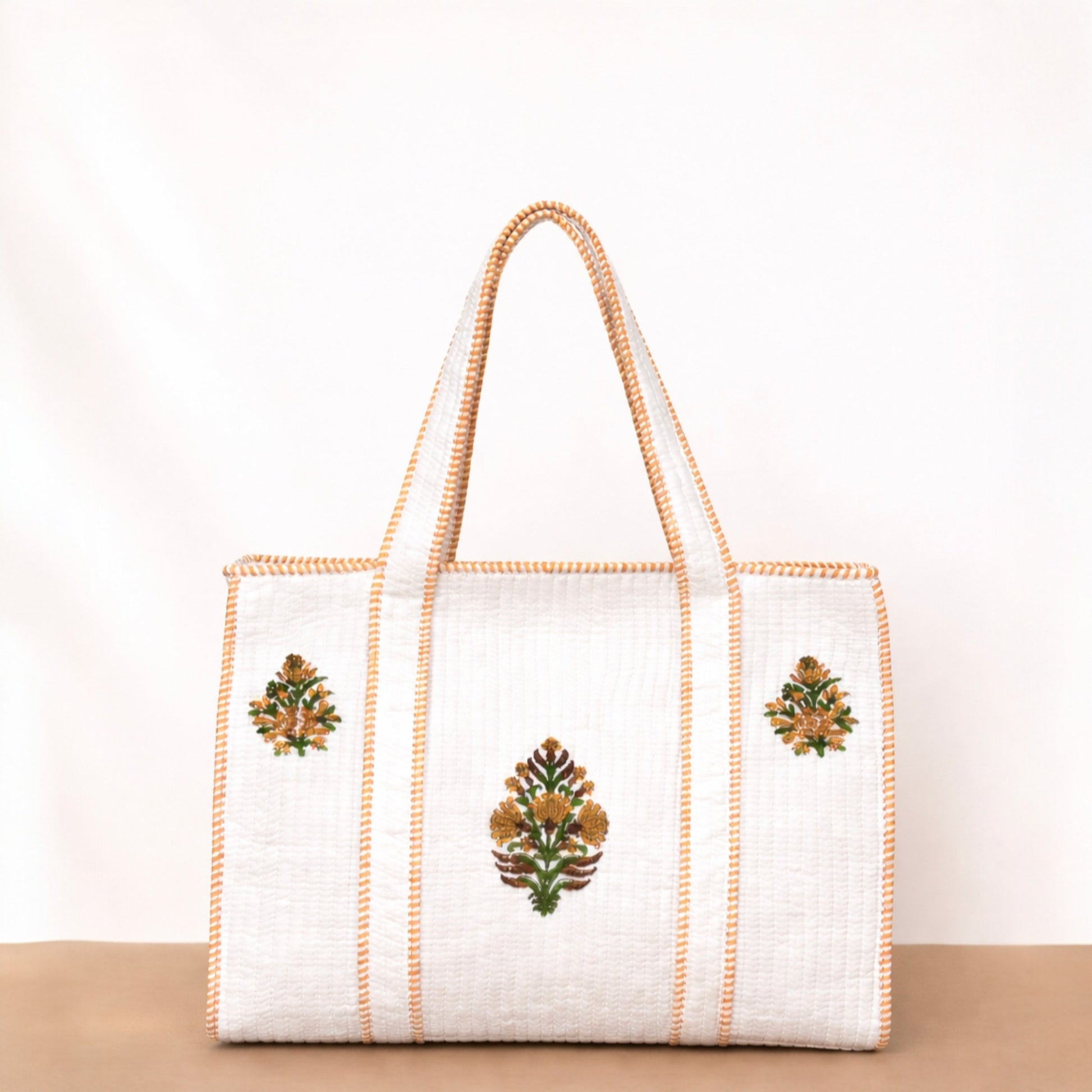 White tote bag with floral embroidery on a beige surface