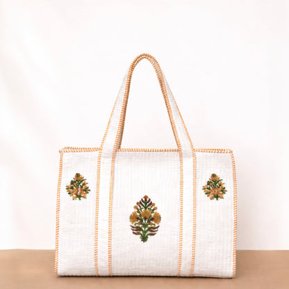 White tote bag with floral embroidery on a beige surface