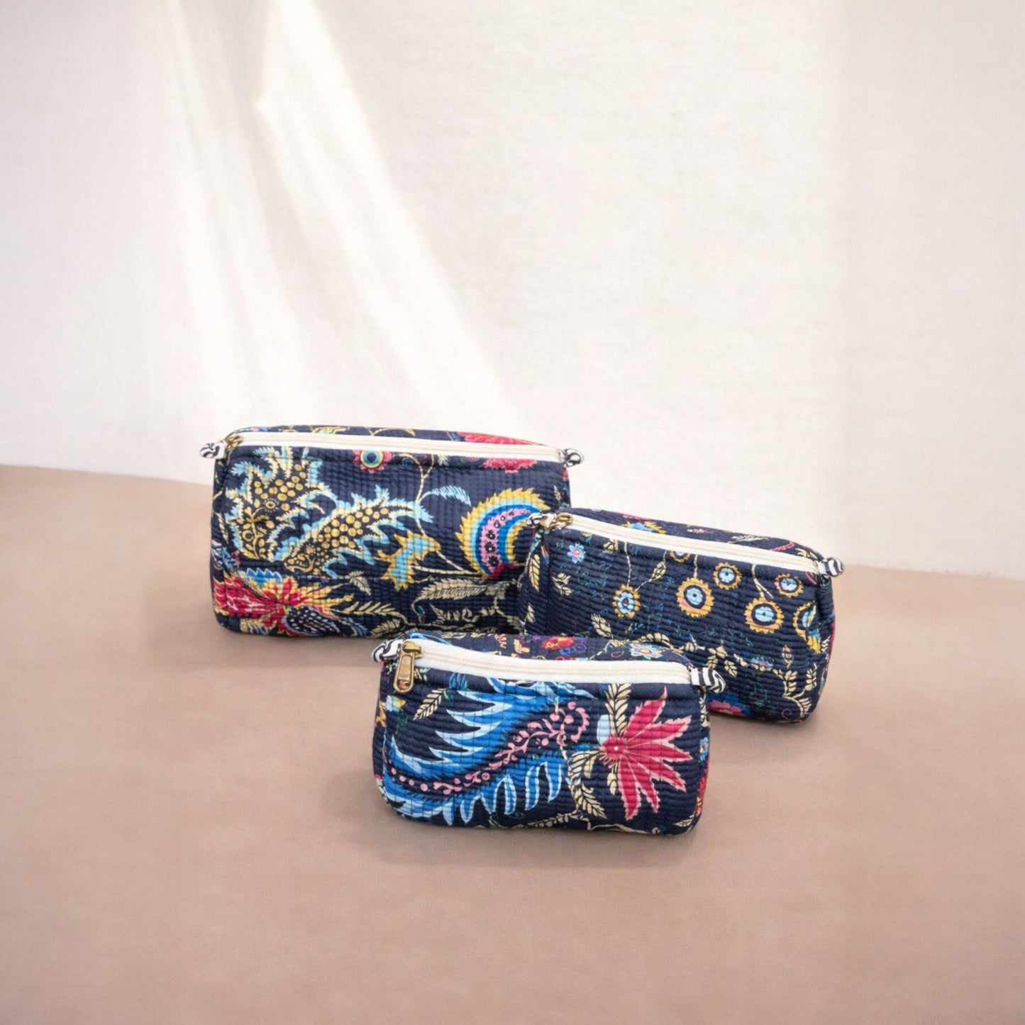 Three floral-patterned pouches on a beige surface with a white background