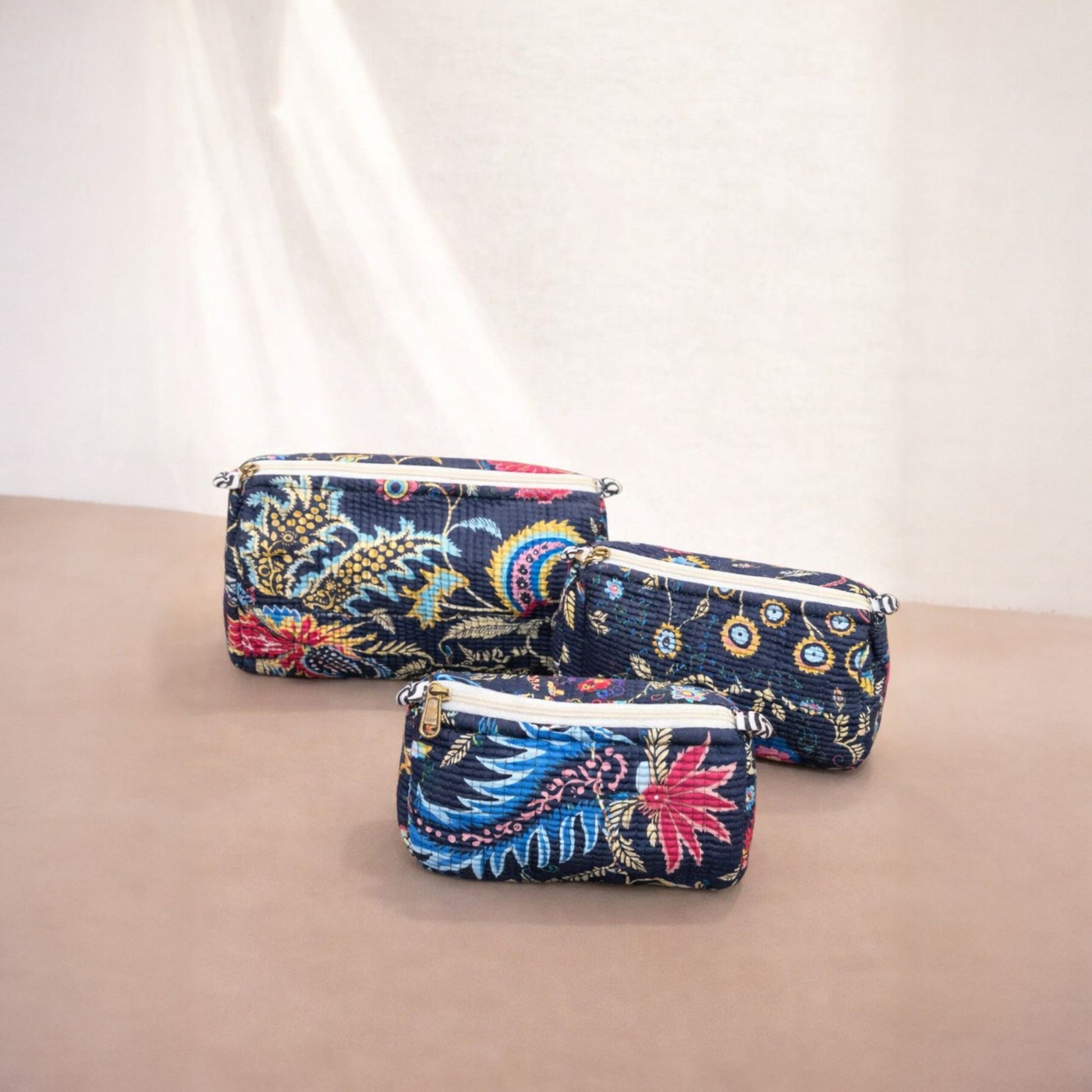 Three floral-patterned pouches on a beige surface with a white background