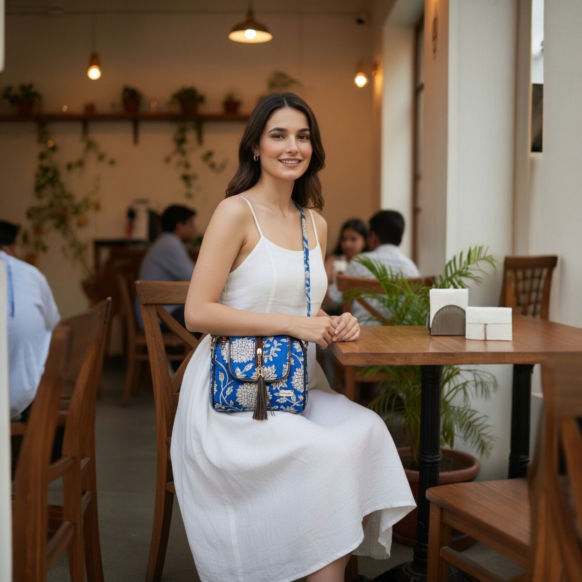 Woman in a white dress holding a blue handbag in a restaurant setting