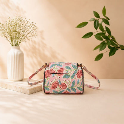 Floral patterned handbag on a beige surface with a vase and plant in the background