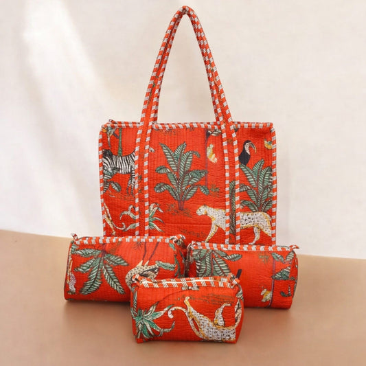 Set of three red fabric bags with animal and leaf patterns on a beige surface.