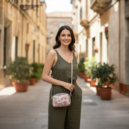 Woman in green outfit with floral handbag walking down a sunlit street.
