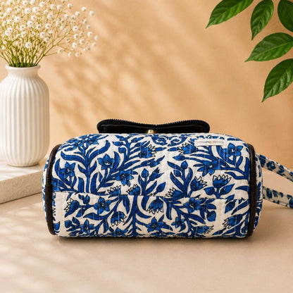 Floral patterned bag on a beige surface with a vase and plant in the background