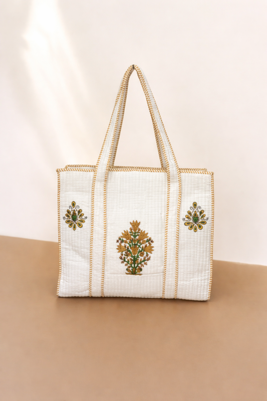 White tote bag with gold embroidery on a beige background