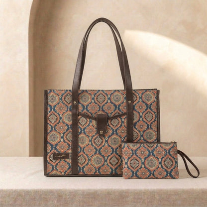 A patterned tote bag with dark brown leather handles and trim, shown alongside a matching zip pouch on a beige surface against a softly lit neutral background.