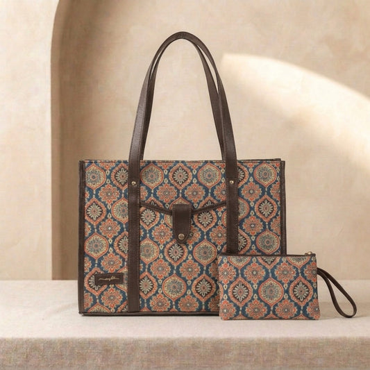 A patterned tote bag with dark brown leather handles and trim, shown alongside a matching zip pouch on a beige surface against a softly lit neutral background.