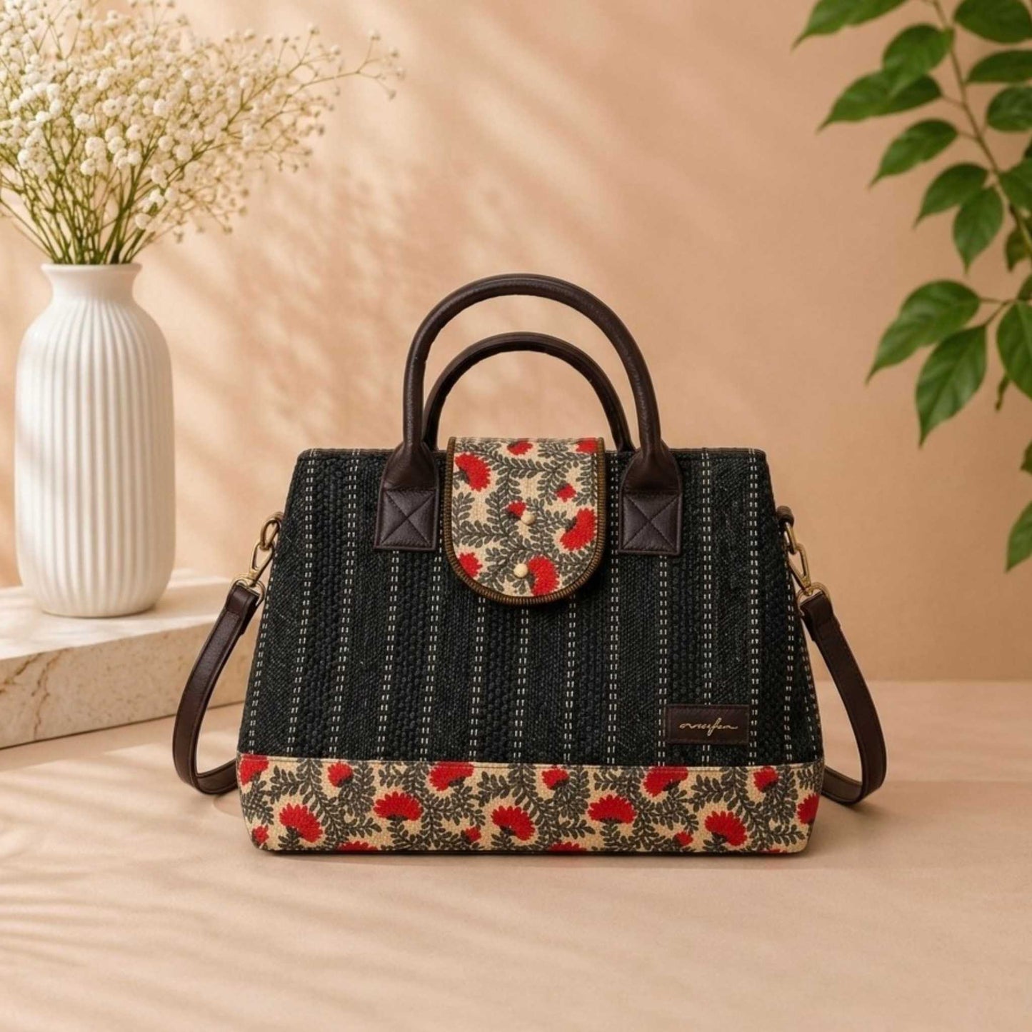 Floral-patterned handbag on a beige surface with a vase and plant in the background