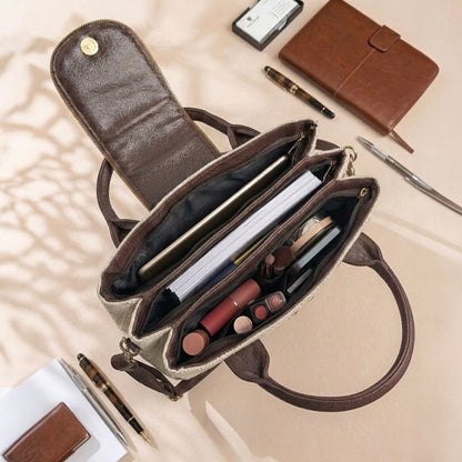 Open brown handbag with makeup items on a beige surface