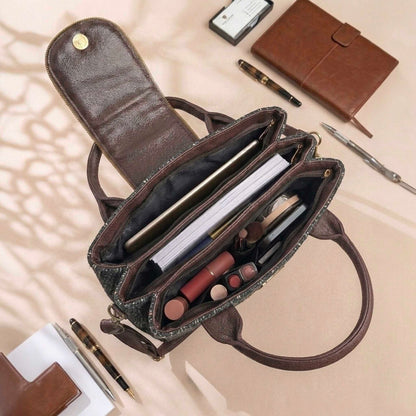 Open brown handbag with makeup and stationery items on a beige surface