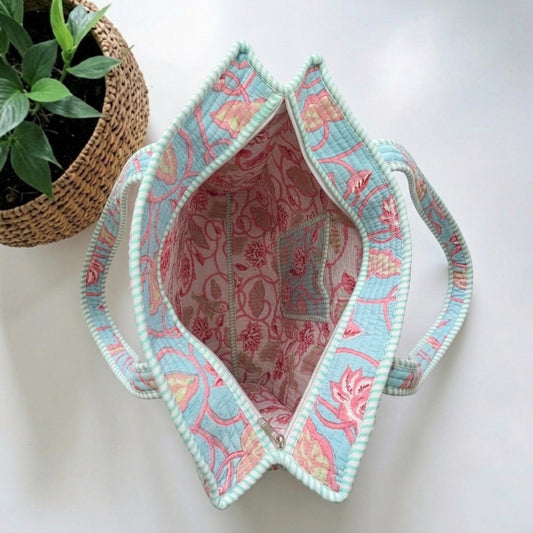 Handcrafted tote features a quilted cotton construction with a vibrant floral print & functional zipper closure