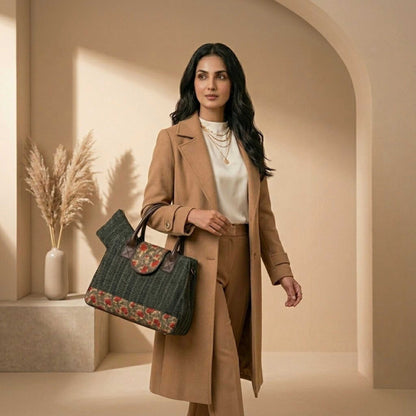 Woman in a beige coat holding a patterned handbag in a warm-toned interior setting