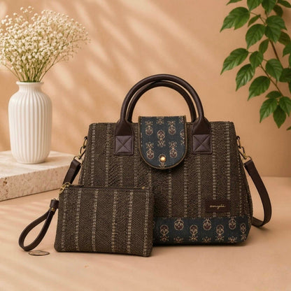 Dark textured handbag with matching pouch on a beige surface, with a vase and plant in the background.