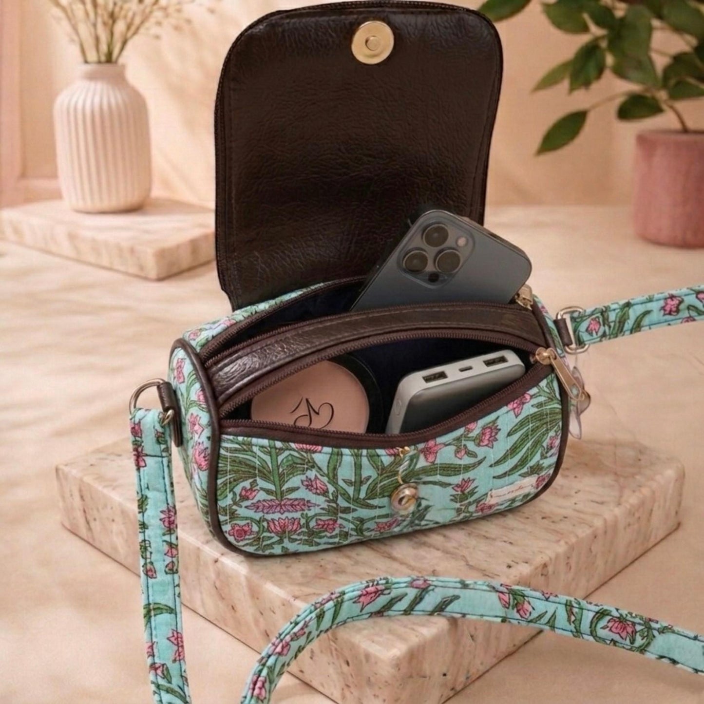 Floral-patterned crossbody bag with phone inside on a wooden surface