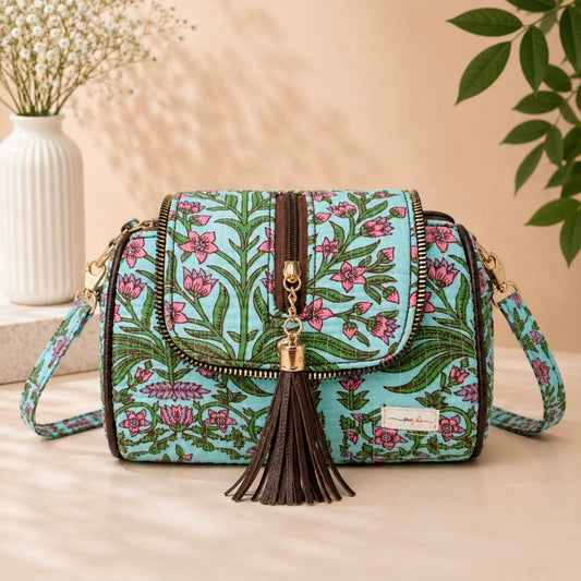 Floral patterned handbag with tassel on a beige surface with decorative elements.