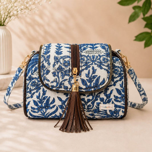 Blue floral patterned handbag with a tassel on a beige surface
