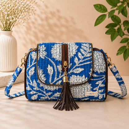 Blue floral patterned handbag with tassel on a neutral background